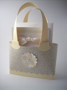 a paper bag with a bow on the front and flower on the inside, sitting on a table