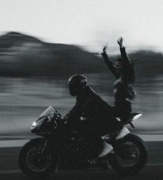 a person on a motorcycle with their arms in the air and one hand raised up