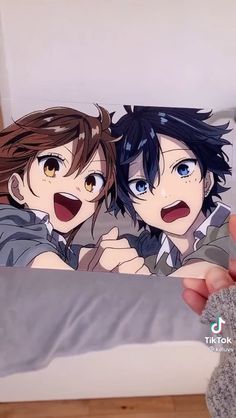 someone holding up a pillow with two anime characters on it's face and one is pointing at the camera