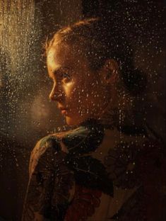 a woman standing in front of a window with rain coming down on her face and head