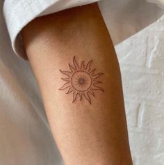 a woman's arm with a small sun tattoo on the left side of her arm