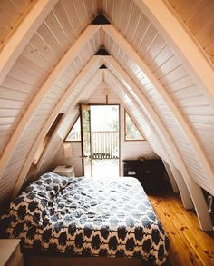 an attic bedroom with wooden floors and white walls, has a large bed in the center