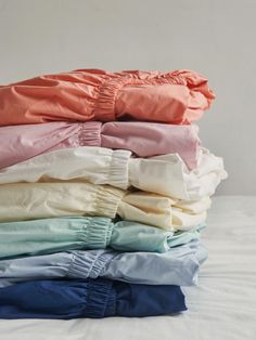 a stack of folded clothes sitting on top of a bed