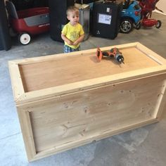 a young boy standing in front of a wooden box