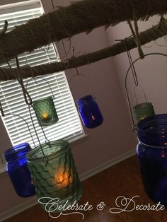 blue jars are hanging from a tree branch with candles in them and the words celebrate & decorate above them