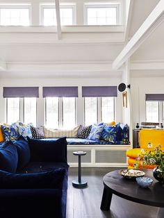 a living room with blue couches and yellow pillows on the windowsills,