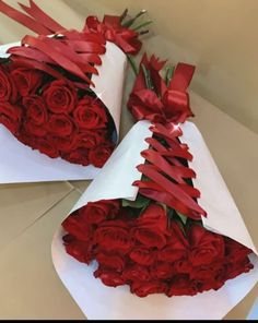 two large bouquets of red roses wrapped in white paper