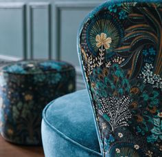 a blue velvet chair and footstool sitting next to each other on a wooden table