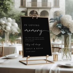 a sign that says in loving memory sitting on top of a table next to a vase with flowers