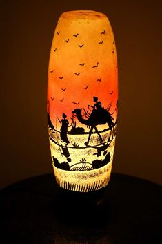 a glass vase with an image of people on horseback riding through the water at sunset