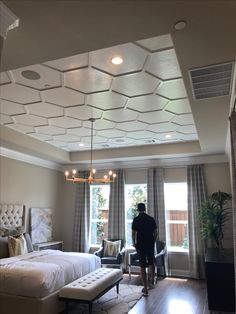 a man is standing in the middle of a room with two beds and a couch