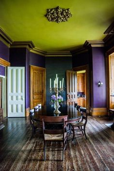 a dining room with purple walls and wooden floors