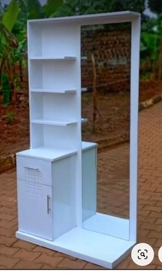 a white bookcase sitting on top of a brick sidewalk