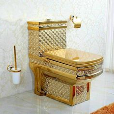 a gold toilet in the middle of a white room with an orange rug on the floor