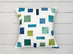 a white pillow with green and blue squares on it