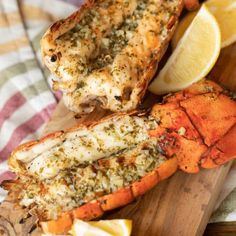 cooked lobsters on a cutting board with lemon wedges and parmesan cheese