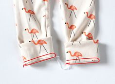 two pairs of flamingos printed on white leggings with red piping around the legs