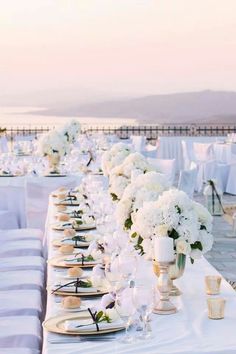 a long table is set up with white flowers and place settings