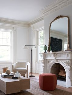 a living room filled with furniture and a fire place in front of a mirror on the wall