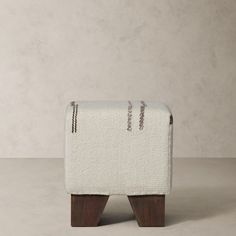 an upholstered foot stool made out of wood and fabric