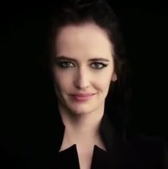 a woman with dark hair and green eyes smiling at the camera while wearing a black shirt