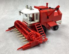 a red and white toy tractor with spikes on it