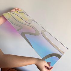 a woman holding up a piece of paper with an abstract painting on it's side