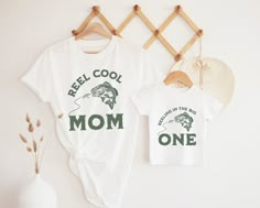 two t - shirts that say reel cool and mom on the front, one with a fish