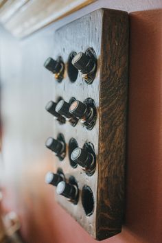 a close up of a wooden board with many knobs on it and a wall in the background