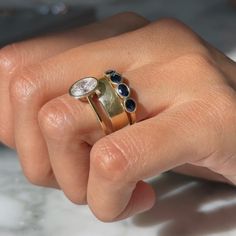 a woman's hand holding two rings with blue and white stones on the sides