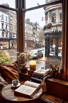 a coffee table in front of a window with a book on it next to a candle