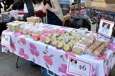 an outdoor market with people shopping and selling goods on the tables in front of them