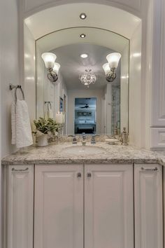 a large bathroom with marble counter tops and white cabinets, along with two lights on either side of the mirror