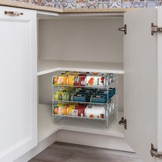 an open cabinet in a kitchen filled with canned food