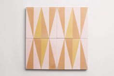 three square tiles with yellow and pink designs on the front, one has an abstract design