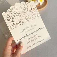 a person holding up a white wedding card