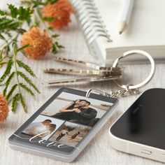 a personalized photo keychain is shown next to a phone and flowers on a table