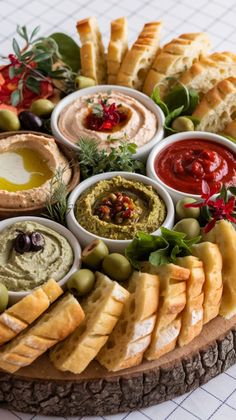 a platter filled with different types of dips and bread on top of a table