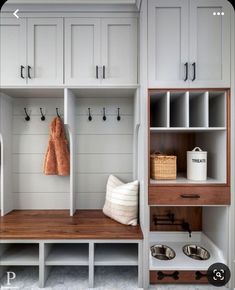 an organized mud room with white cabinets and wood flooring