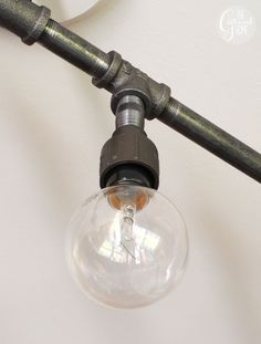 an old fashioned light bulb is attached to a wall mounted lamp with a metal pipe