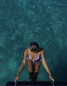 a woman standing in the water looking down at her feet and arms, from above