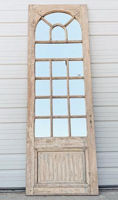 an old wooden door with a mirror on the front and side window panes above it