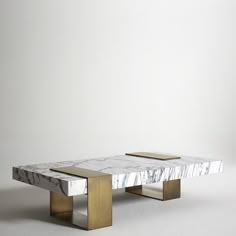 a marble coffee table with gold legs on a white surface in front of a plain wall