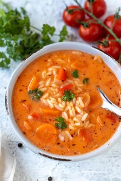 a white bowl filled with soup next to some tomatoes and parsley on the side