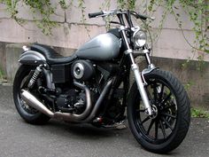 a black motorcycle parked in front of a building with ivy growing on the wall behind it