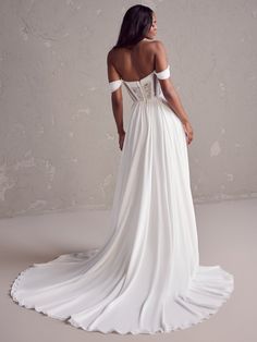 a woman in a white wedding dress looking off to the side with her back turned