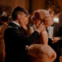 a man in a tuxedo and a woman in a fur stoler dance together