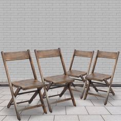 three wooden chairs sitting next to each other on a tile floor in front of a brick wall