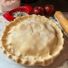 an uncooked pie sitting on top of a table next to a rolling pin