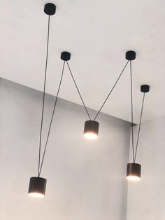 three lights are hanging from the ceiling in a room with white walls and flooring